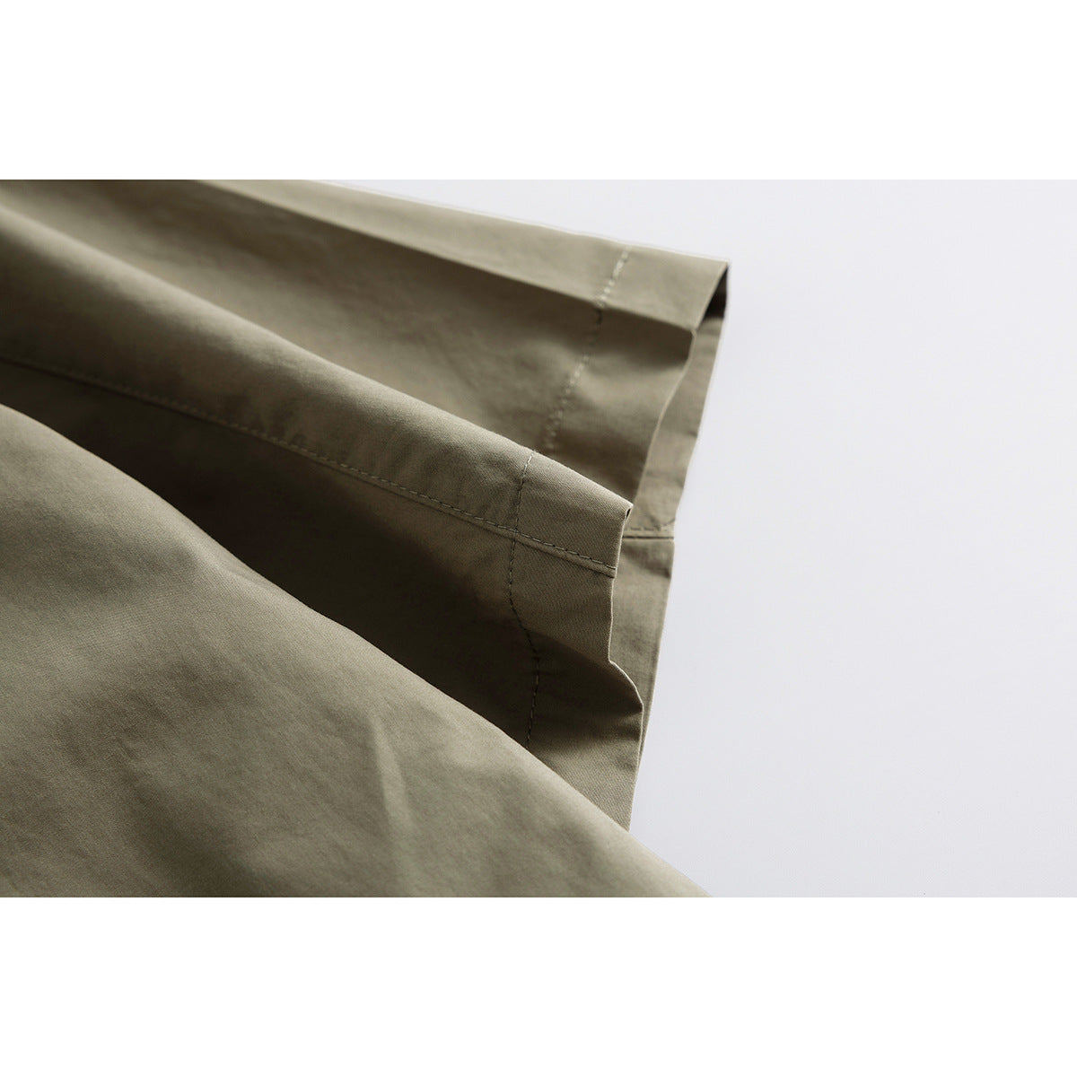 Close-up of the olive-khaki shirt sleeve hem and stitching.