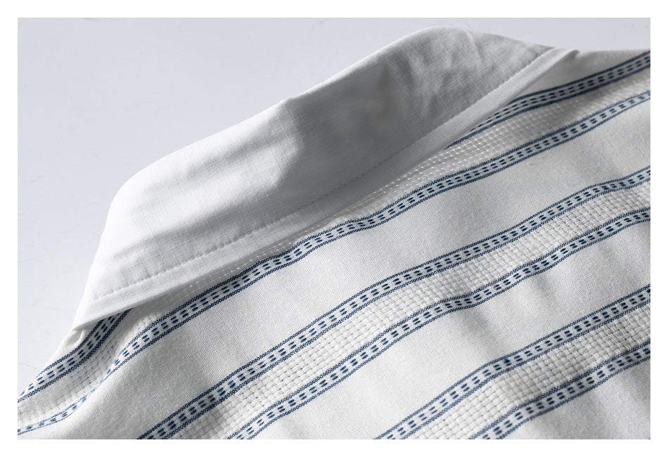 Close-up of the folded collar and blue striped fabric of a white shirt.