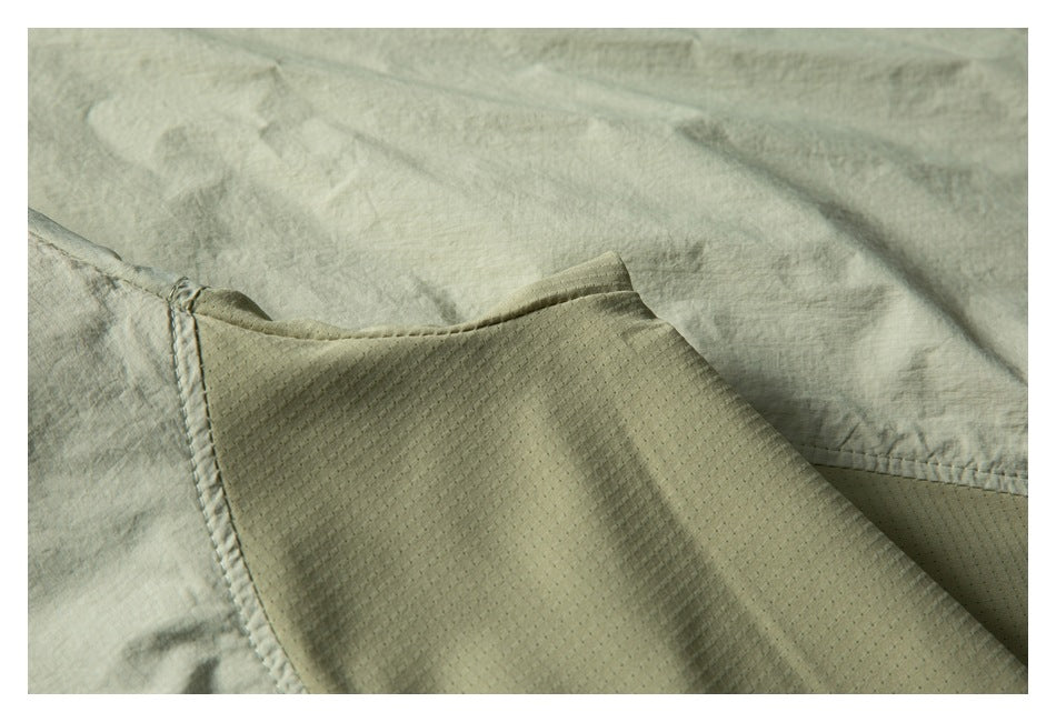 Close-up of pale sage garment fabric, a stitched seam, and a textured inner panel.