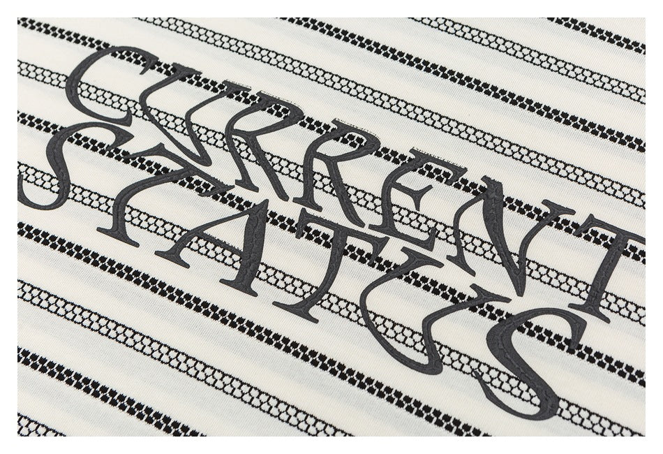 Close-up of raised dark lettering across black patterned stripes on ivory fabric.