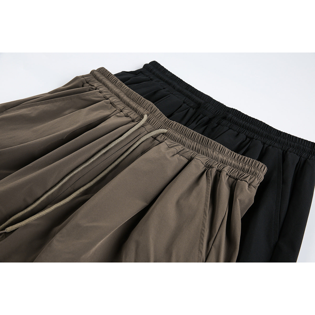 Close-up of taupe and black shorts showing gathered elastic waistbands and a taupe drawstring.