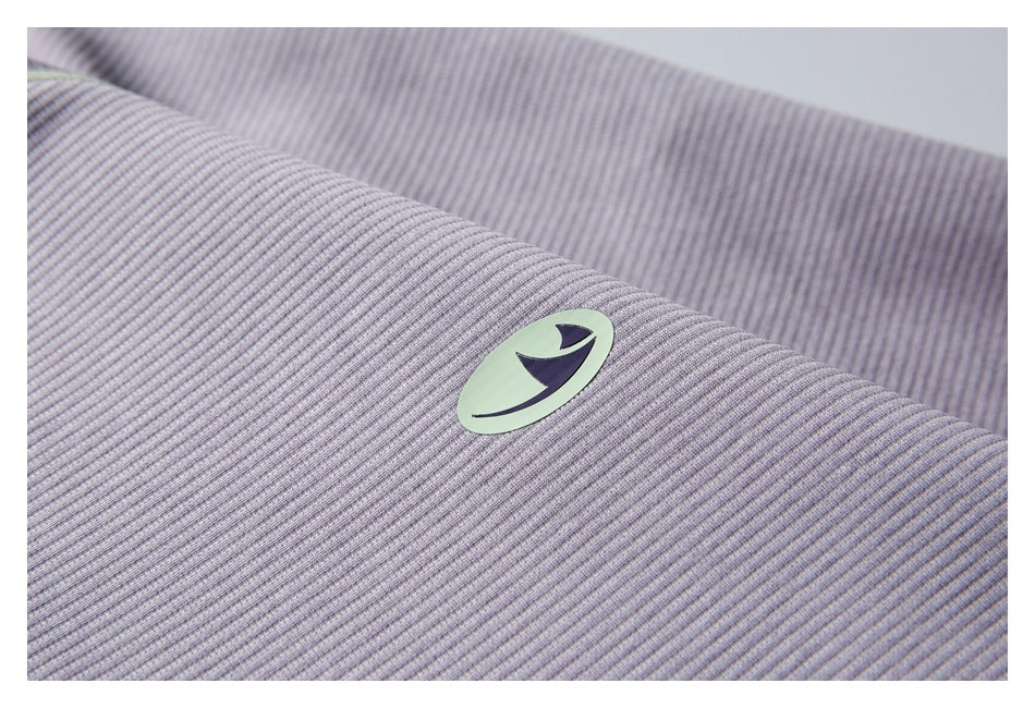Close-up of a pale lavender-gray ribbed garment with a small oval emblem patch.