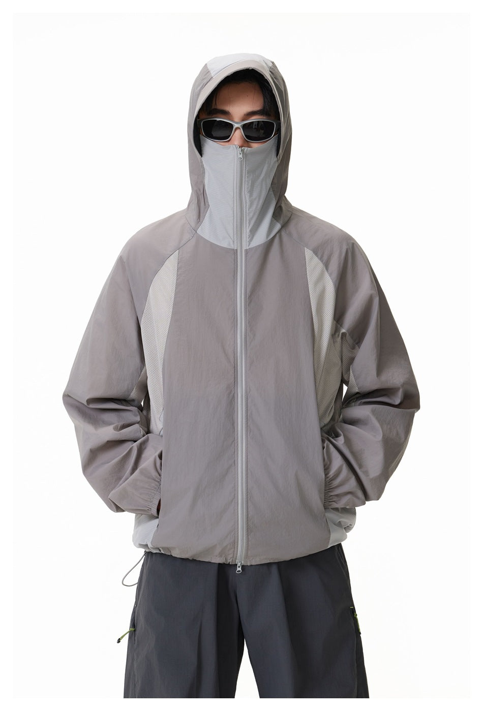 Model wearing a gray zip jacket with pale mesh panels and the hood raised over the high zip collar.