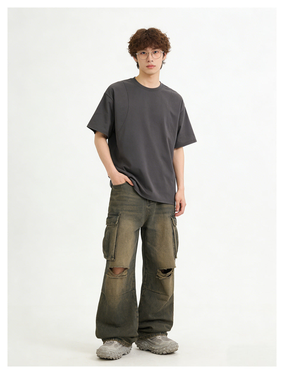 Model wearing a charcoal-gray oversized T-shirt with olive-gray distressed cargo pants, front view.