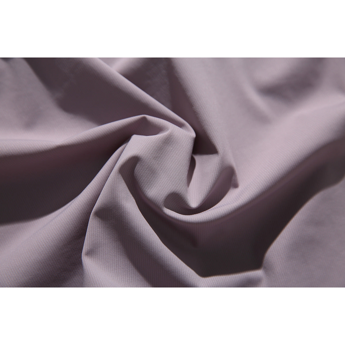 Macro view of dusty mauve shirt fabric draped into soft folds.