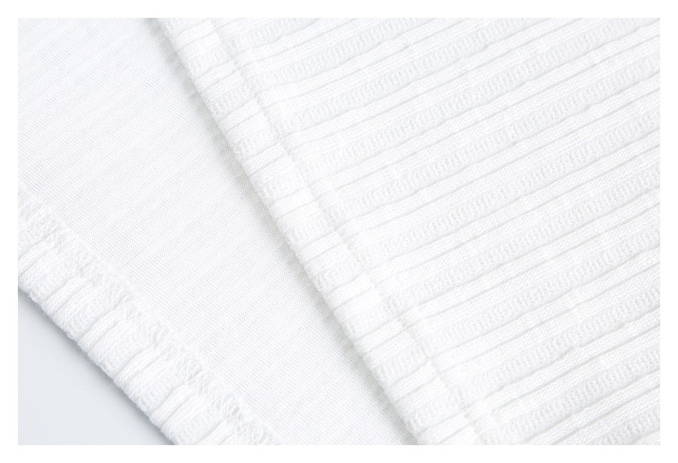 Close-up of white knit fabric showing raised textured bands, a finished edge, and a smooth inner panel.