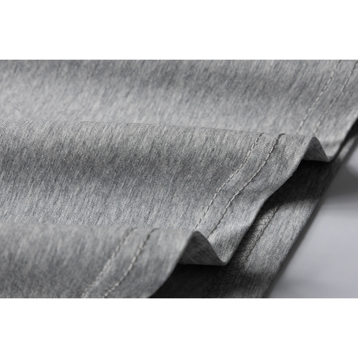 Close-up of the stitched hem and folded edge of gray fabric.