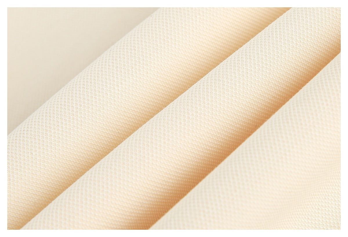 Close-up of cream fabric folded into diagonal ridges, showing its fine textured weave.