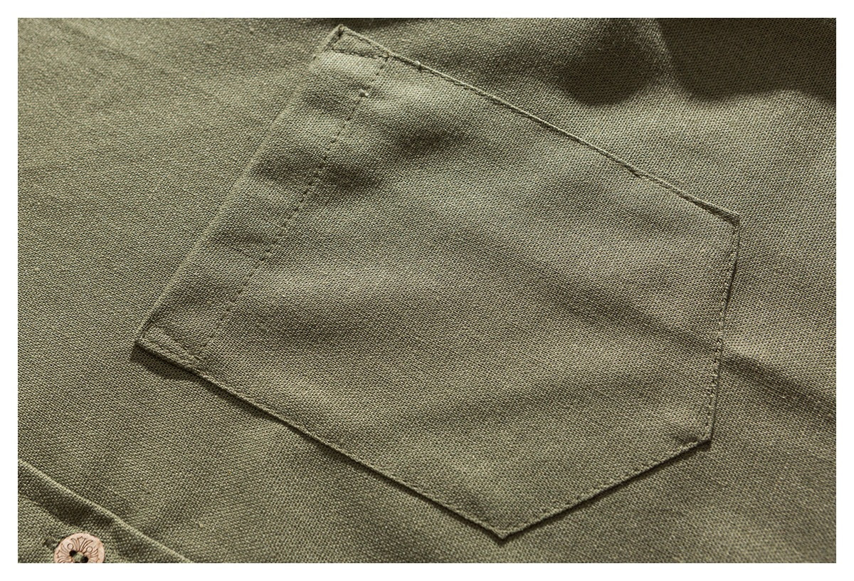 Close-up of the olive shirt's stitched chest pocket and a button near the lower edge.