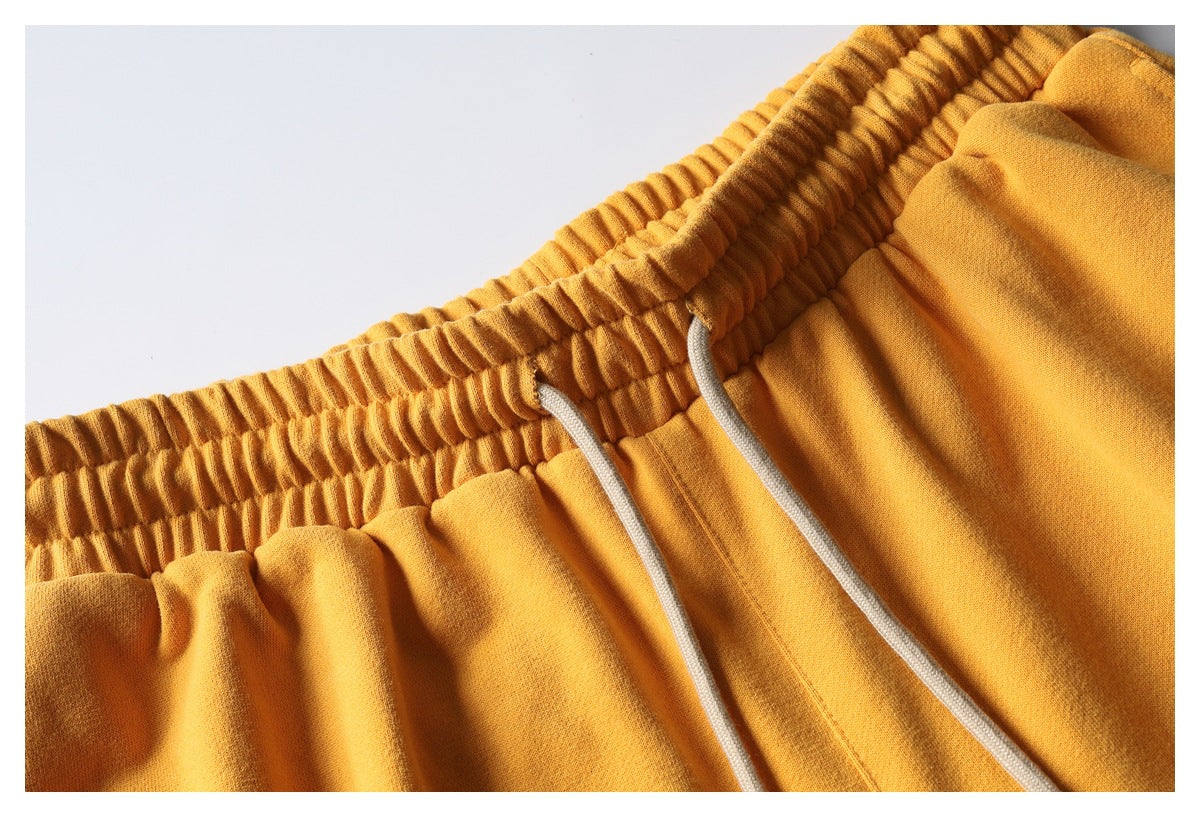 Close-up of mustard-yellow shorts showing a gathered elastic waistband and two white drawstrings.