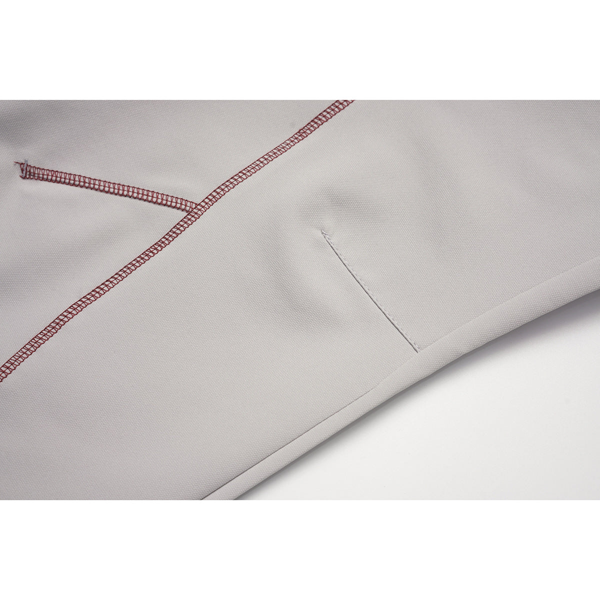 Close-up of light gray pants showing contrasting overlock stitching and a stitched hem.