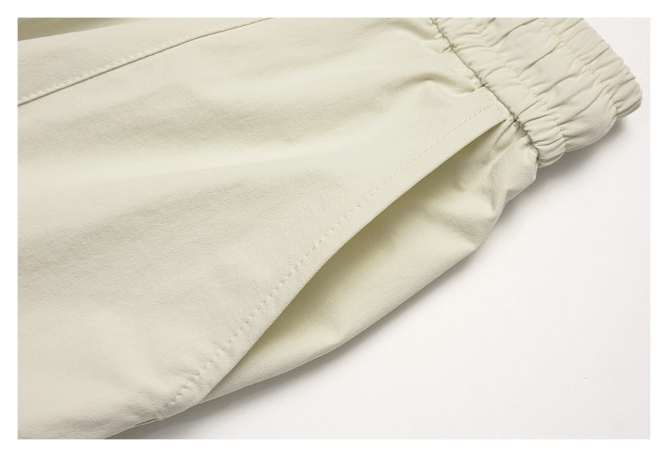 Close-up of an off-white pant leg seam and gathered elastic cuff.