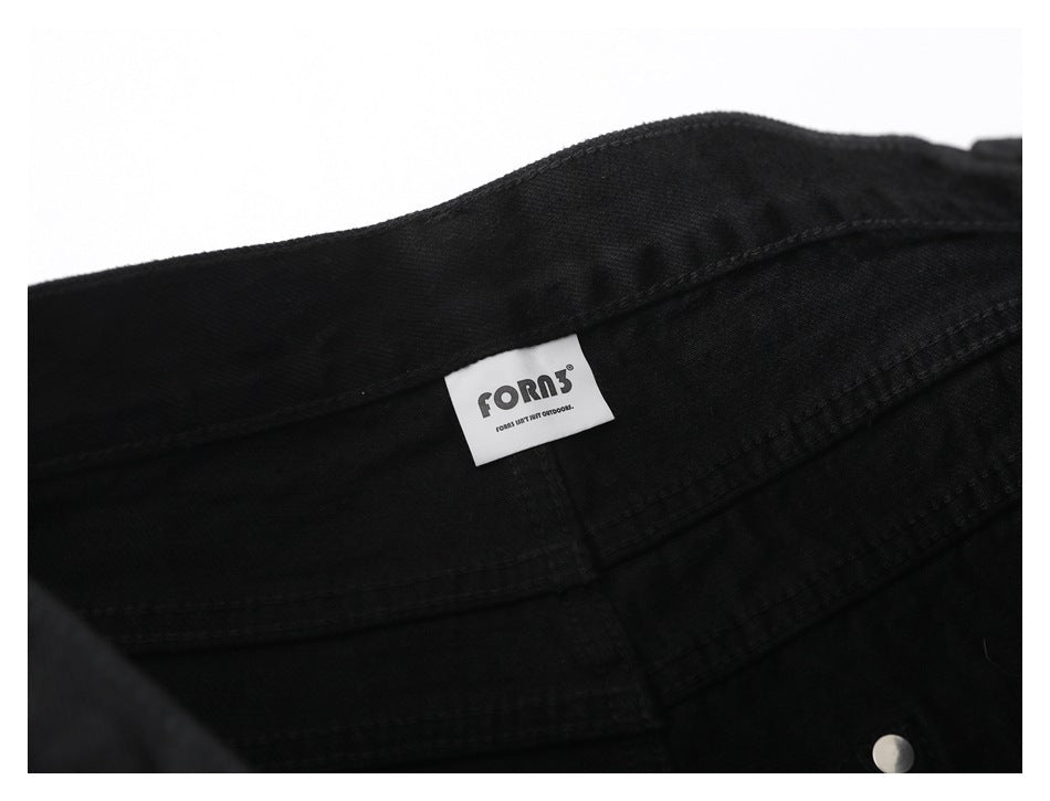 Close-up of black garment fabric with a sewn white FORA label and a silver snap.