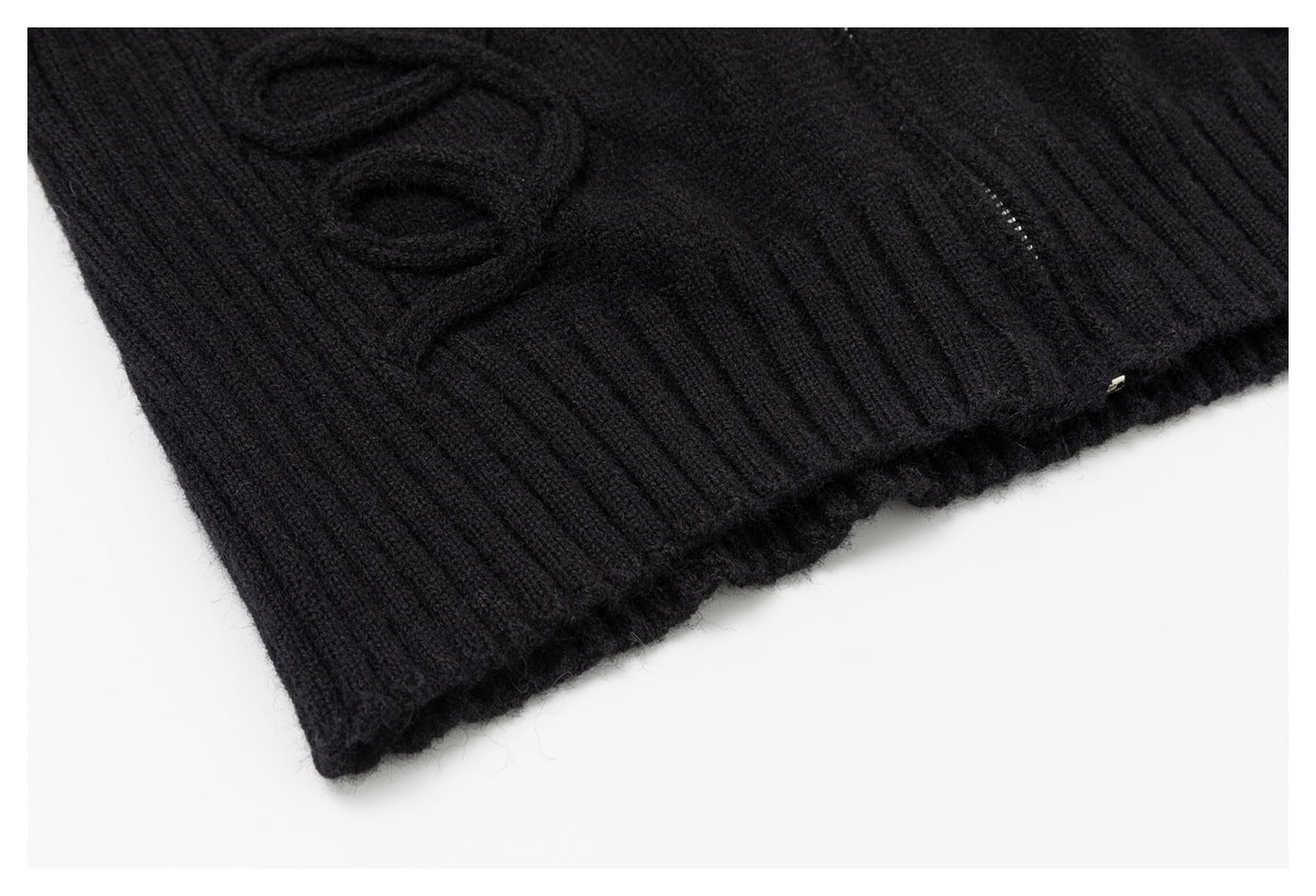 Close-up of a black rib-knit garment hem with raised knit detailing and a small metallic accent.