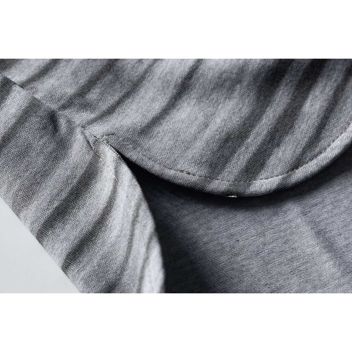 Close-up showing the curved stitched hem and striped fabric of a gray T-shirt.