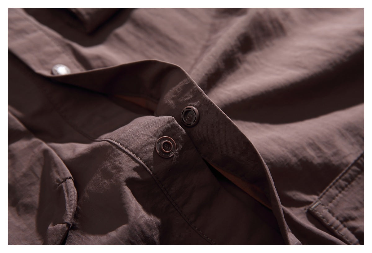 Close-up of a brown jacket's placket with two dark snap fasteners.