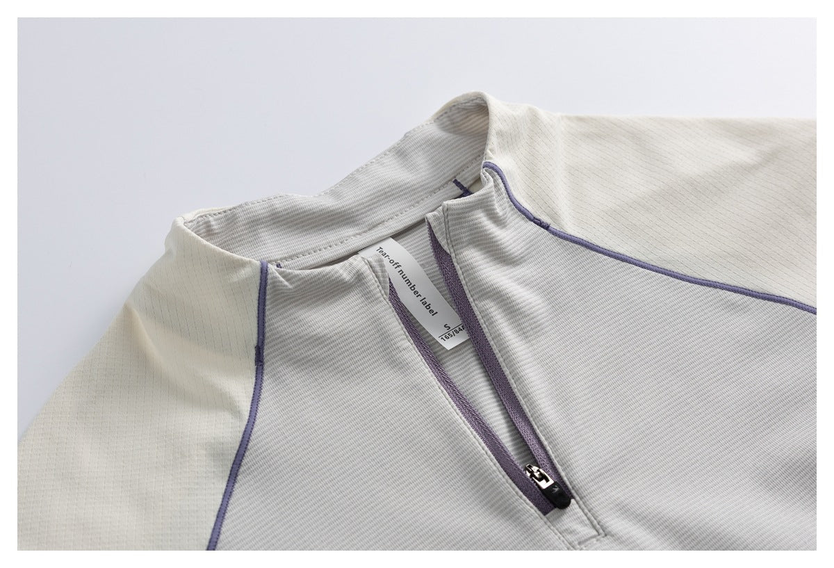 Close-up of an ivory top's short zip neckline with lavender trim and an inner size label.