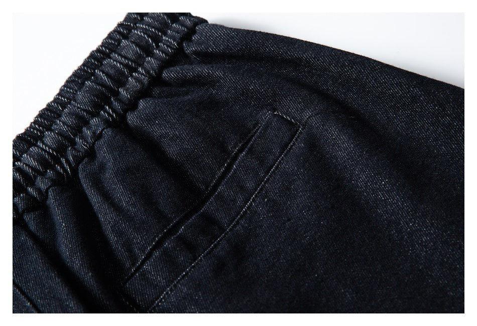 Close-up of a dark indigo pants pocket beside the gathered elastic waistband.