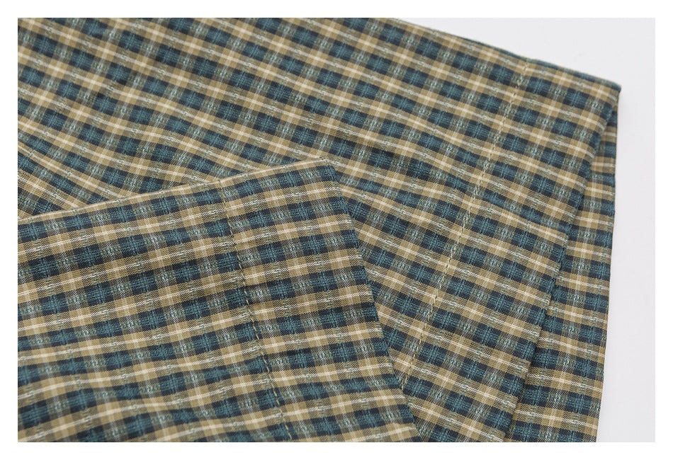 Close-up of a folded cuff and sleeve in blue, tan, and cream plaid.