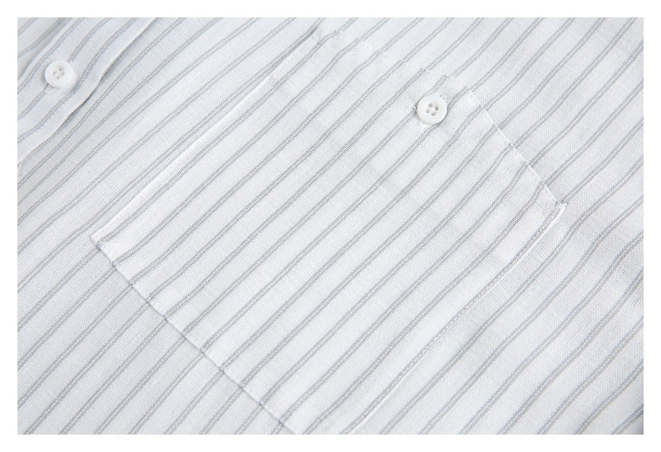 Close-up of a white shirt with fine gray stripes and a single buttoned chest pocket.