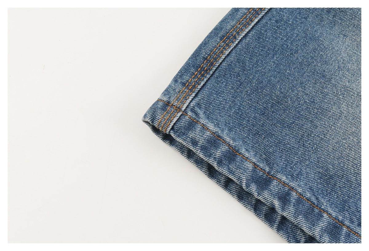 Close-up of blue denim jeans hem with orange-brown stitching.