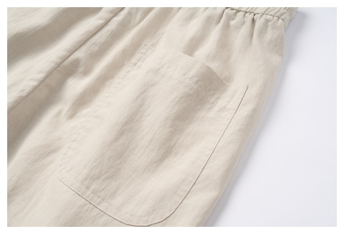 Close-up of a large rounded patch pocket on the cream garment beside its gathered elastic waistband.