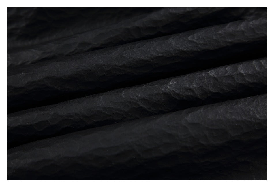 Close-up of black textured garment material arranged in soft folds.