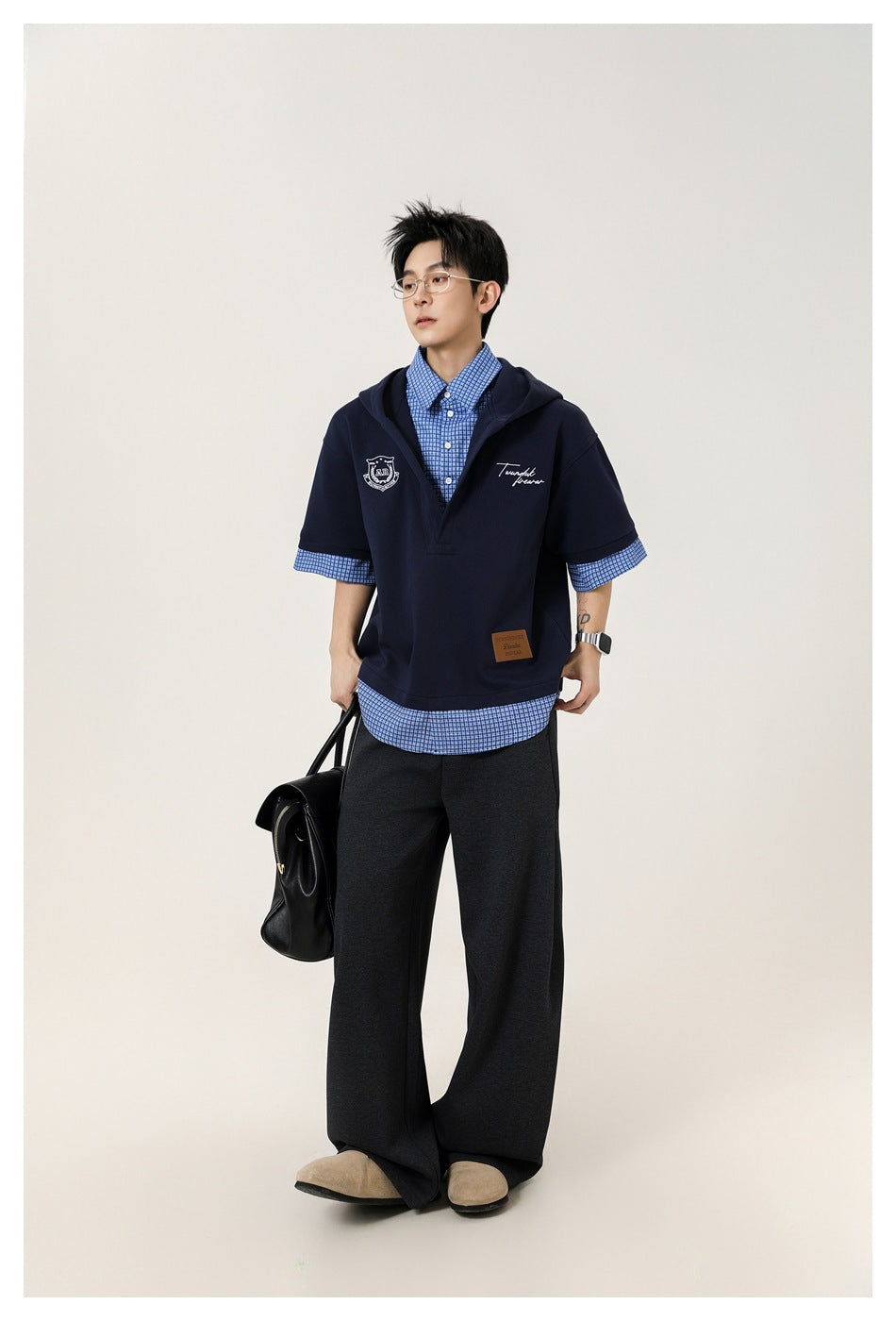 Full-length view of a model wearing a navy hooded pullover over a blue checked shirt.