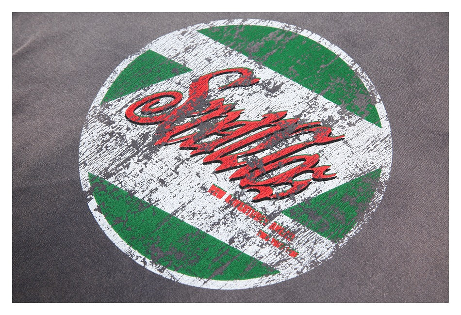 Close-up of a distressed green, white, and red circular graphic on a gray T-shirt.
