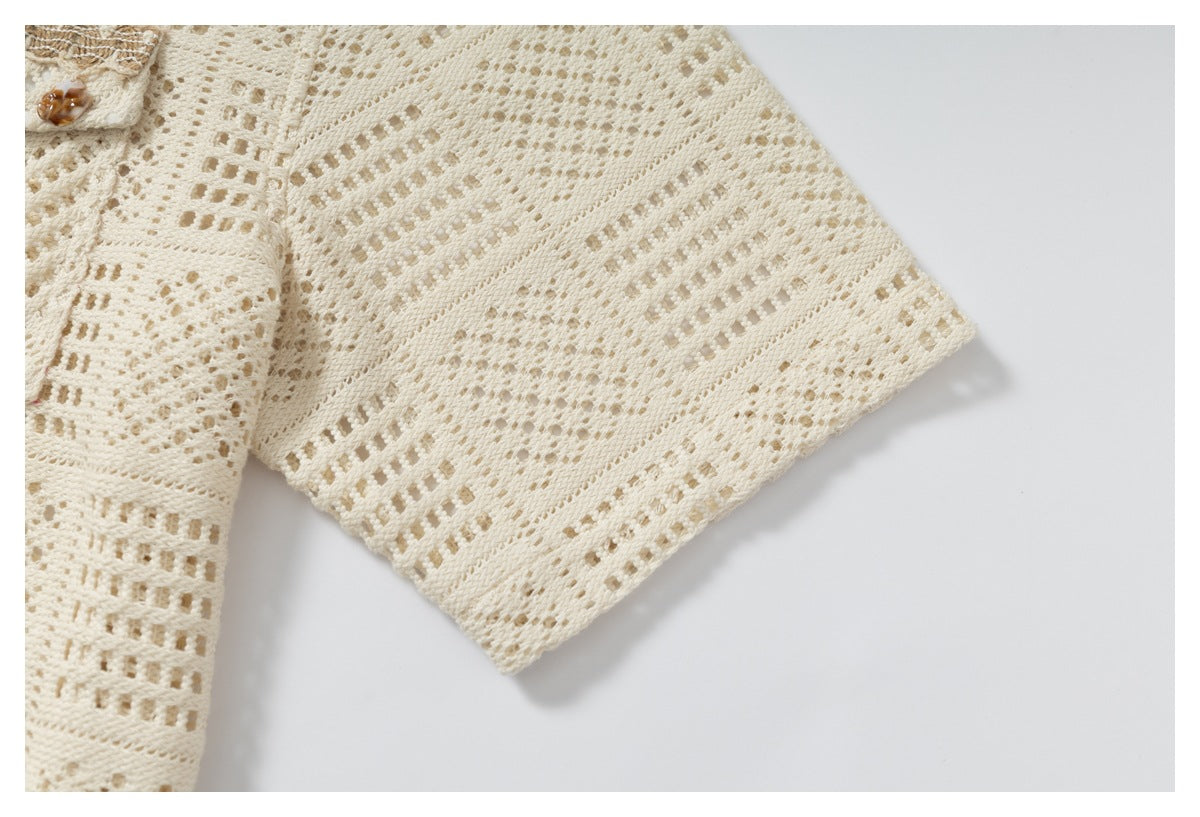 Close-up of the ivory open-knit garment's sleeve and patterned cuff on a white background.