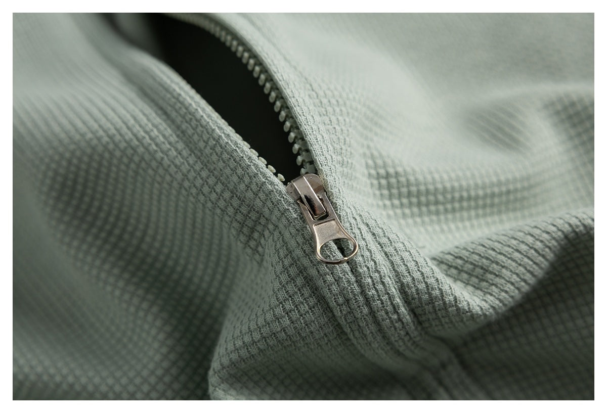 Close-up of the metal zipper and textured sage green fabric on the top.