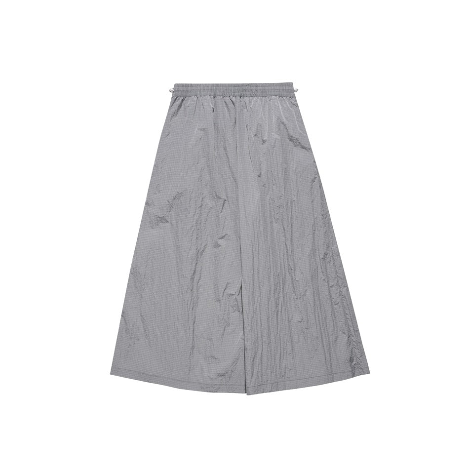 Back view of wide-leg gray pants with a gathered elastic waistband and crinkled, subtly grid-patterned panels.