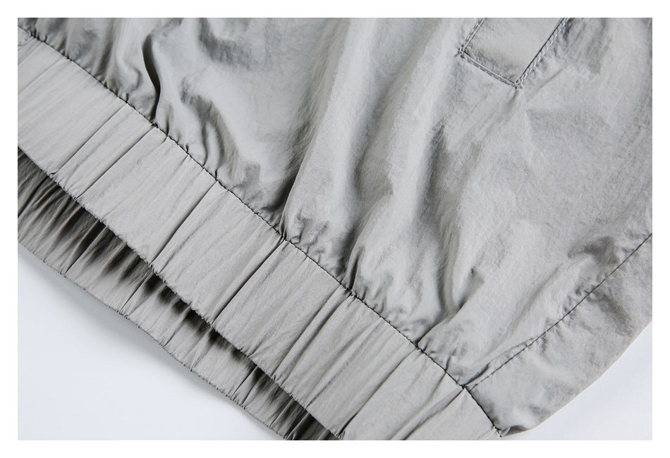 Close-up of the light gray jacket's gathered elastic hem and a nearby pocket corner.
