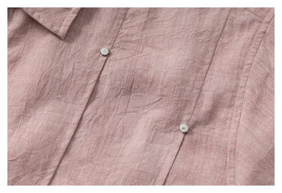 Close-up of a dusty rose garment's button-front placket, collar edge, and small pale buttons.