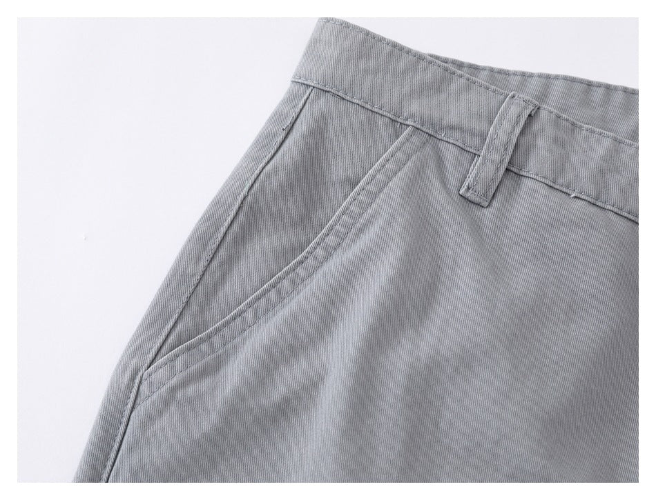 Close-up of gray shorts showing a slanted front pocket, waistband and belt loop.
