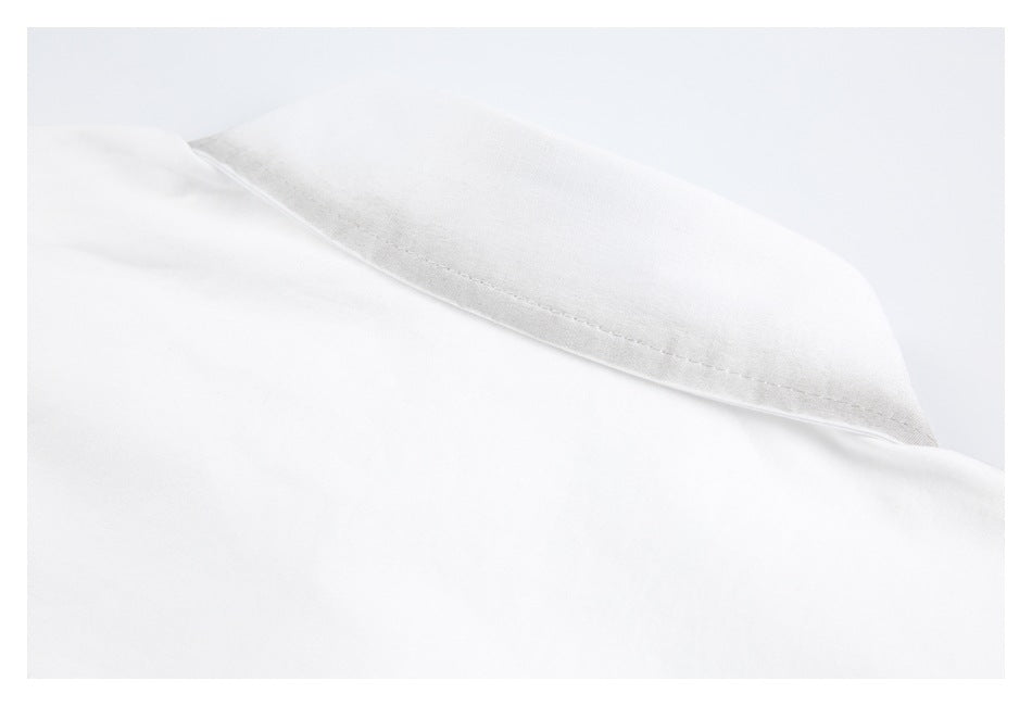 Close-up of a pointed folded collar edge on white fabric, with visible stitching.
