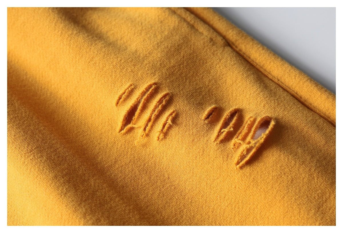 Close-up of mustard-colored fabric with distressed, tone-on-tone stitched lettering.