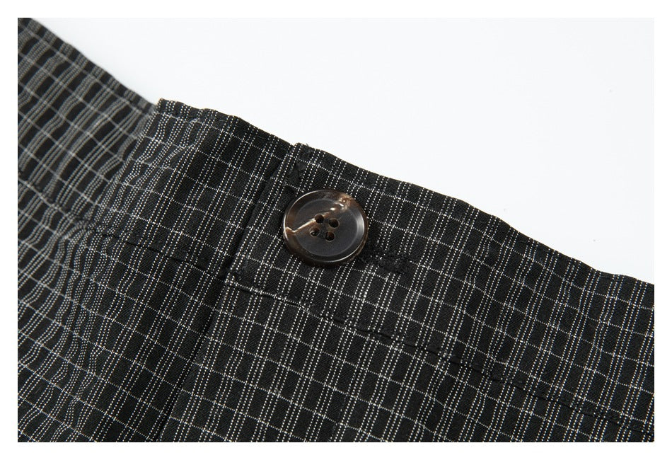Close-up of the dark four-hole waistband button and gray plaid pattern on the shorts.