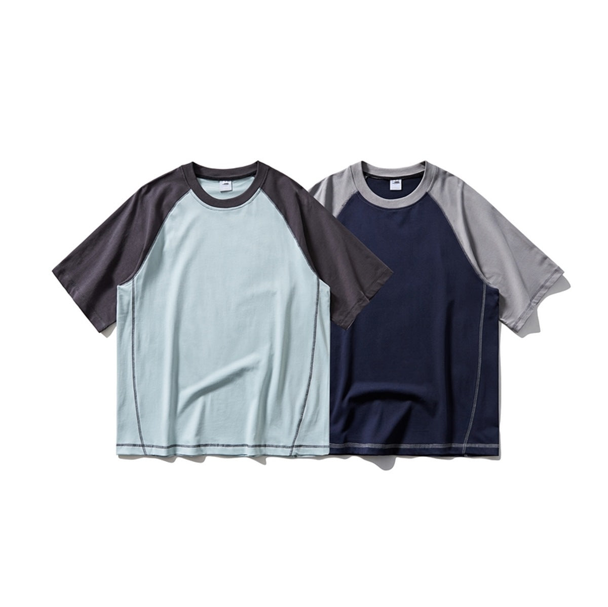 Two short-sleeve raglan T-shirts shown from the front: pale blue with charcoal sleeves and navy with gray sleeves.