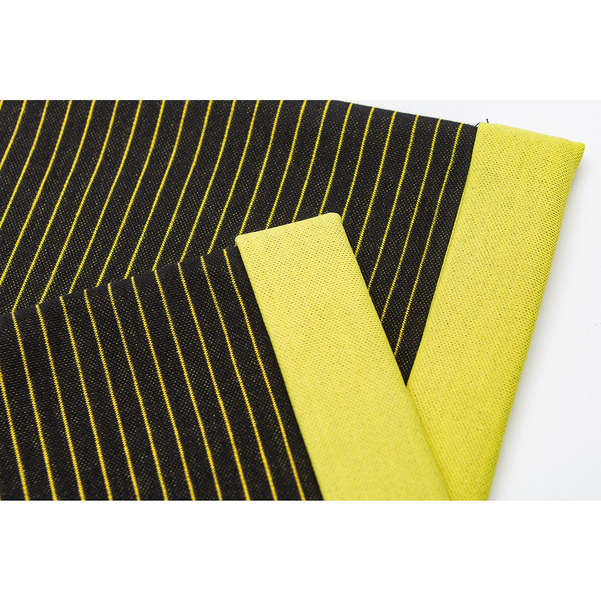 Close-up of black fabric with thin yellow stripes folded to show its bright yellow reverse side.