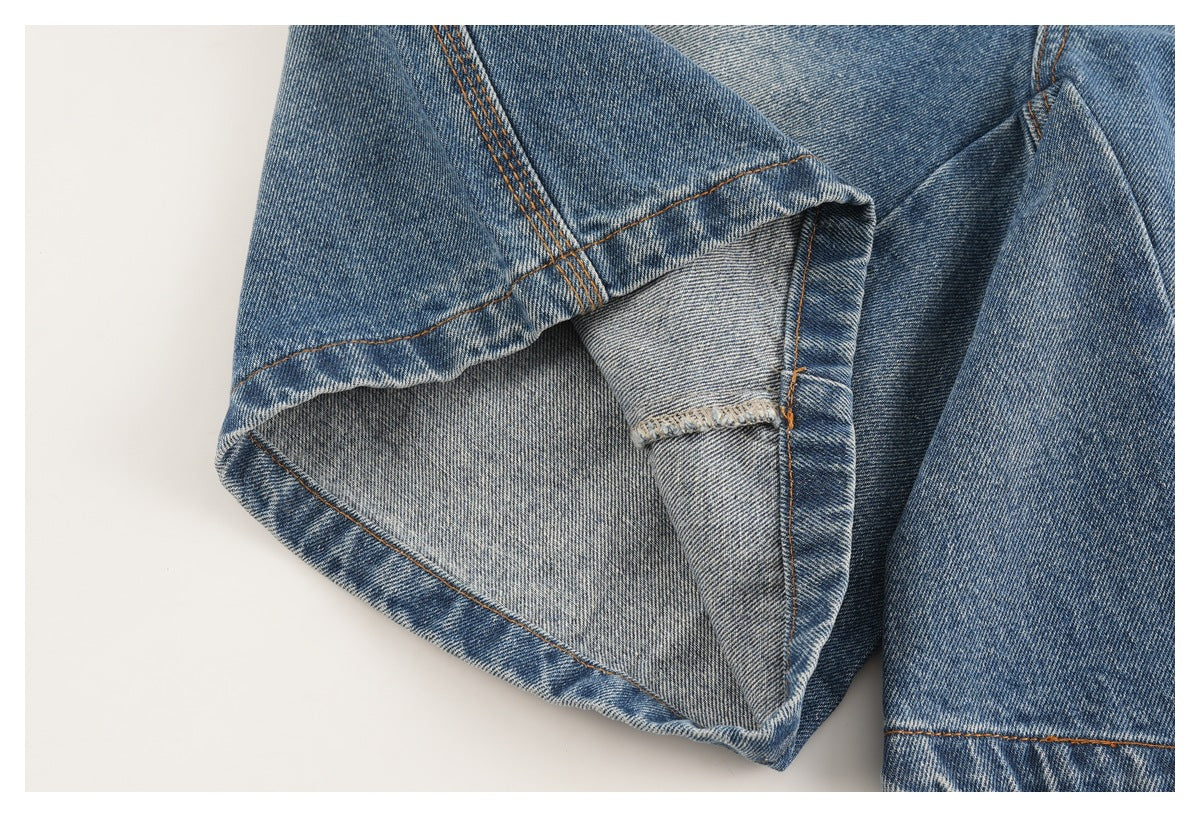Close-up of blue jeans showing folded denim, inner fabric, and orange-brown seam stitching.