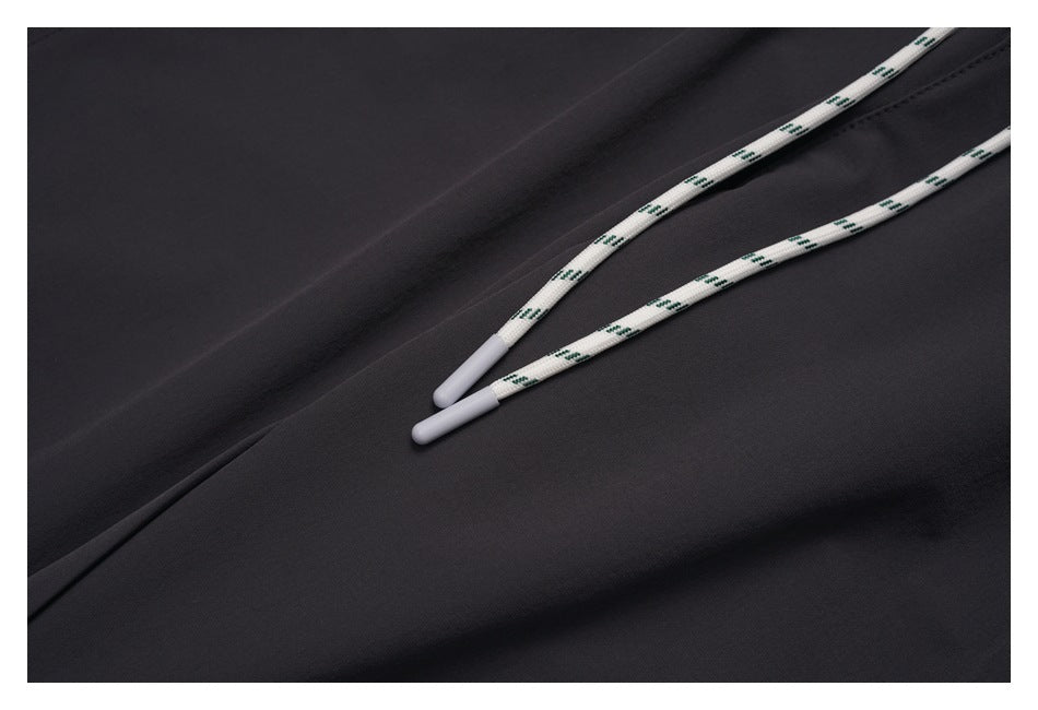 Close-up of white patterned drawstrings with light tips against charcoal pants.