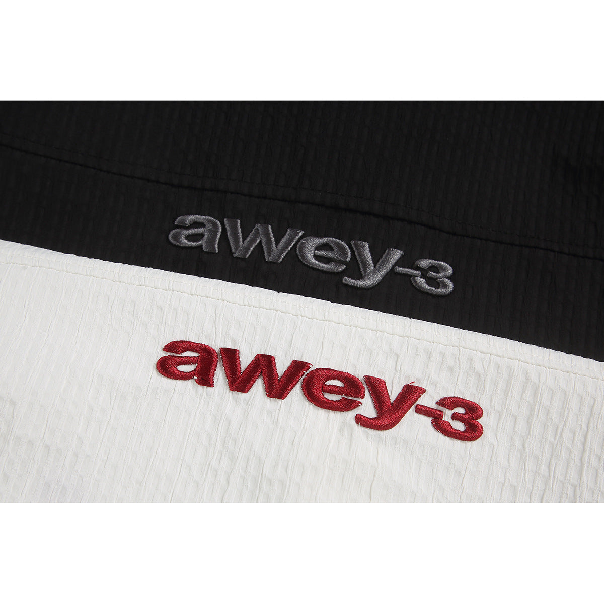 Close-up of gray and red embroidered lettering on black and white shirt fabric.