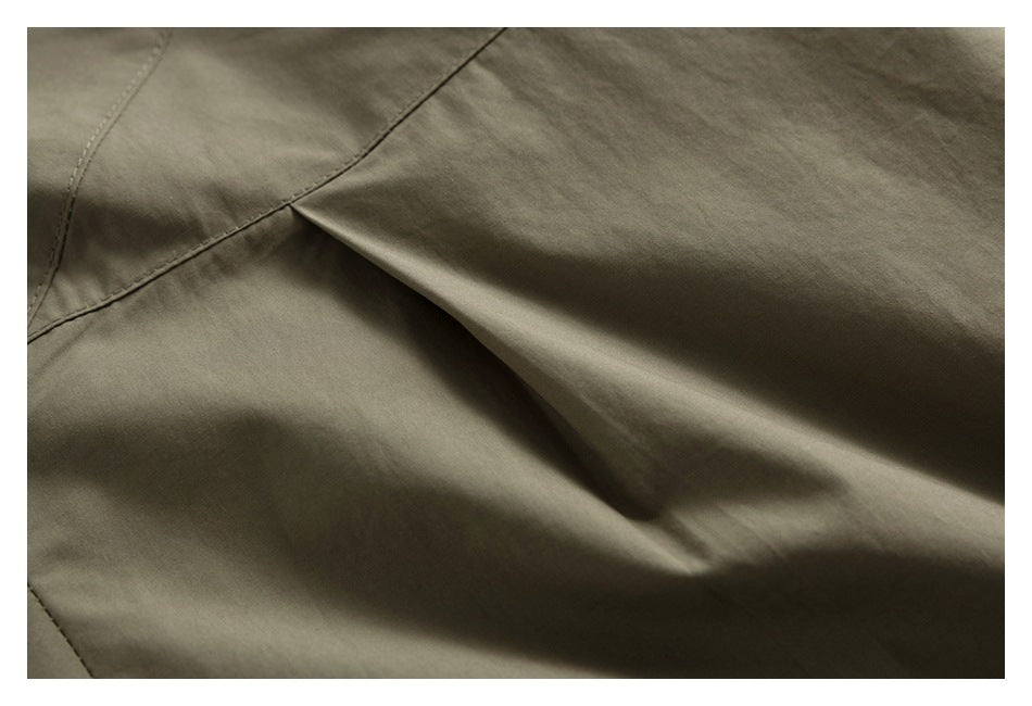 Close-up of an olive-gray garment seam and folded fabric opening.