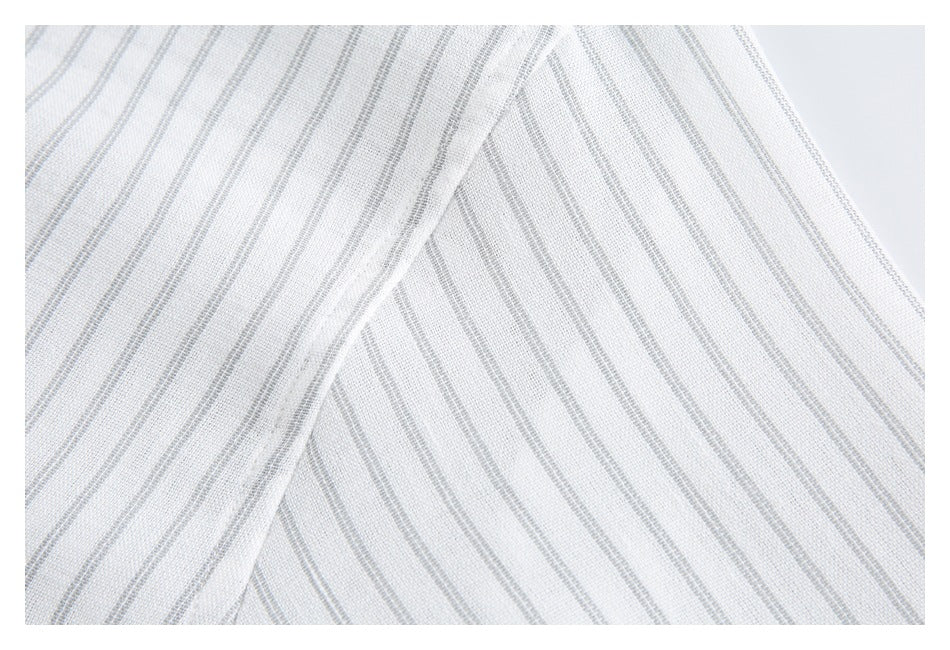 Close-up of white fabric with fine gray stripes, folded to show the striped weave and drape.