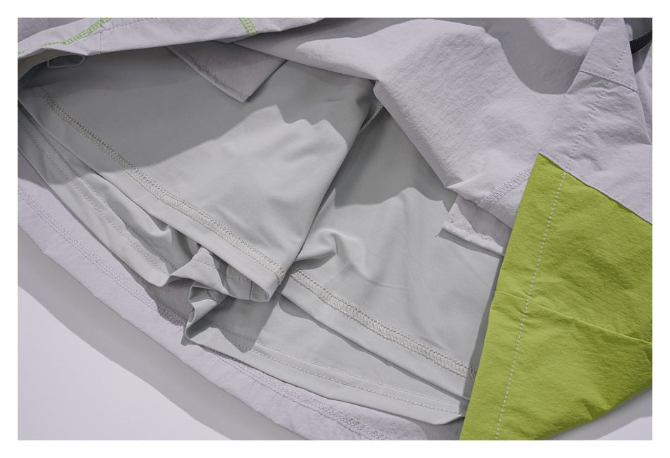 Close-up of layered light gray garment panels with stitched seams beside a lime green panel.