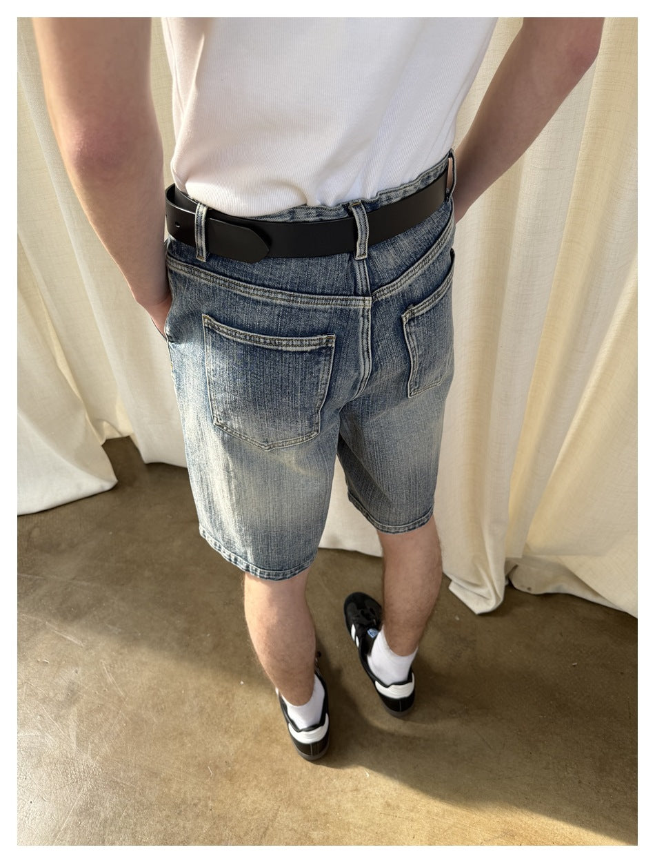 Close rear view of faded blue denim shorts showing two back pockets, waistband and black belt.