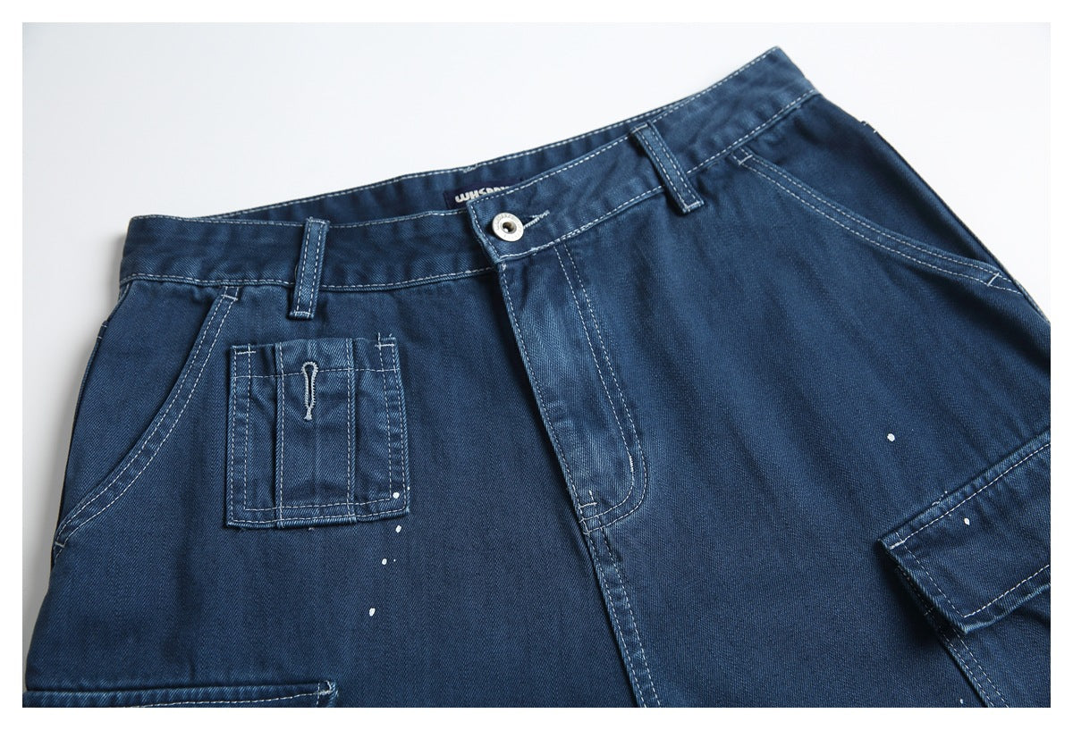 Front close-up of dark blue denim cargo shorts with a button waist, utility pockets, contrast stitching, and white speckles.