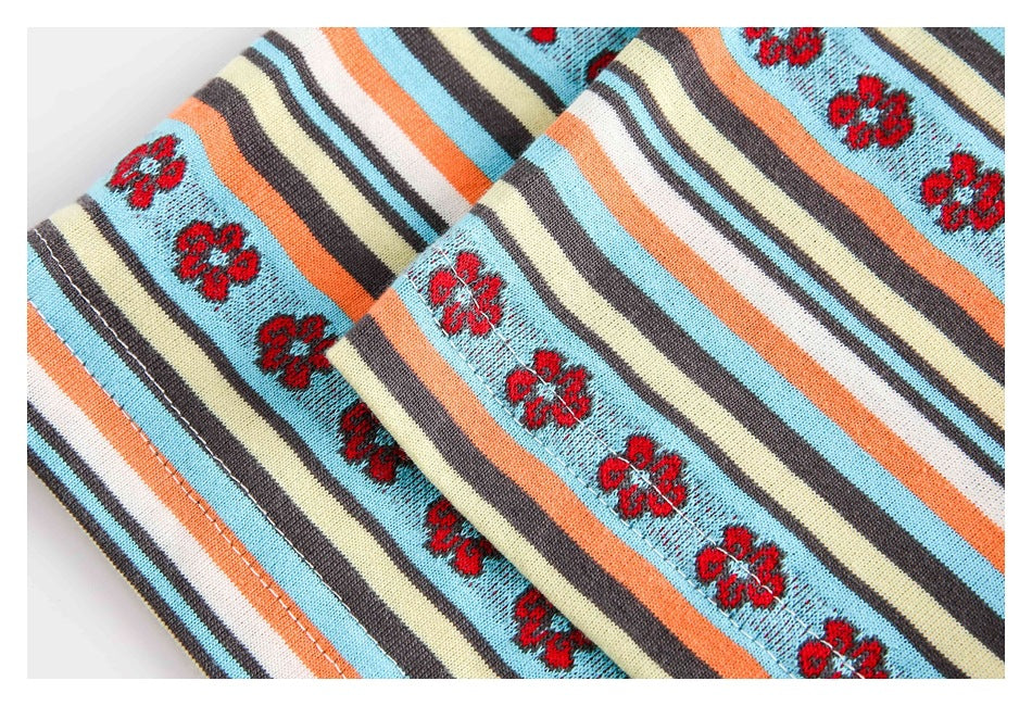 Close-up of overlapping striped knit fabric with red flower motifs and a stitched edge.