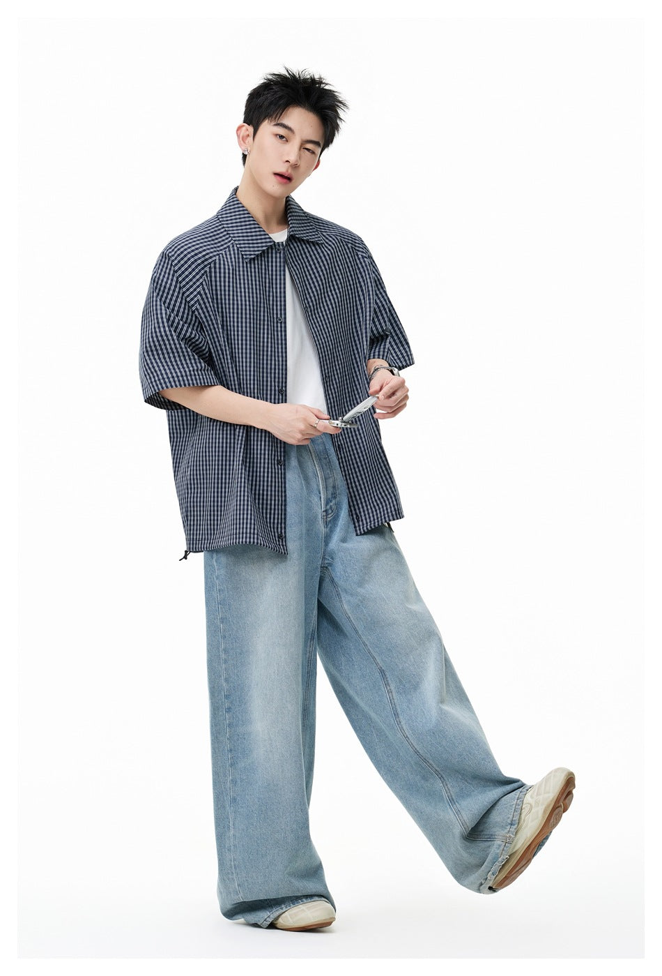 Model wearing a dark navy and white plaid short-sleeve shirt open over a white T-shirt.